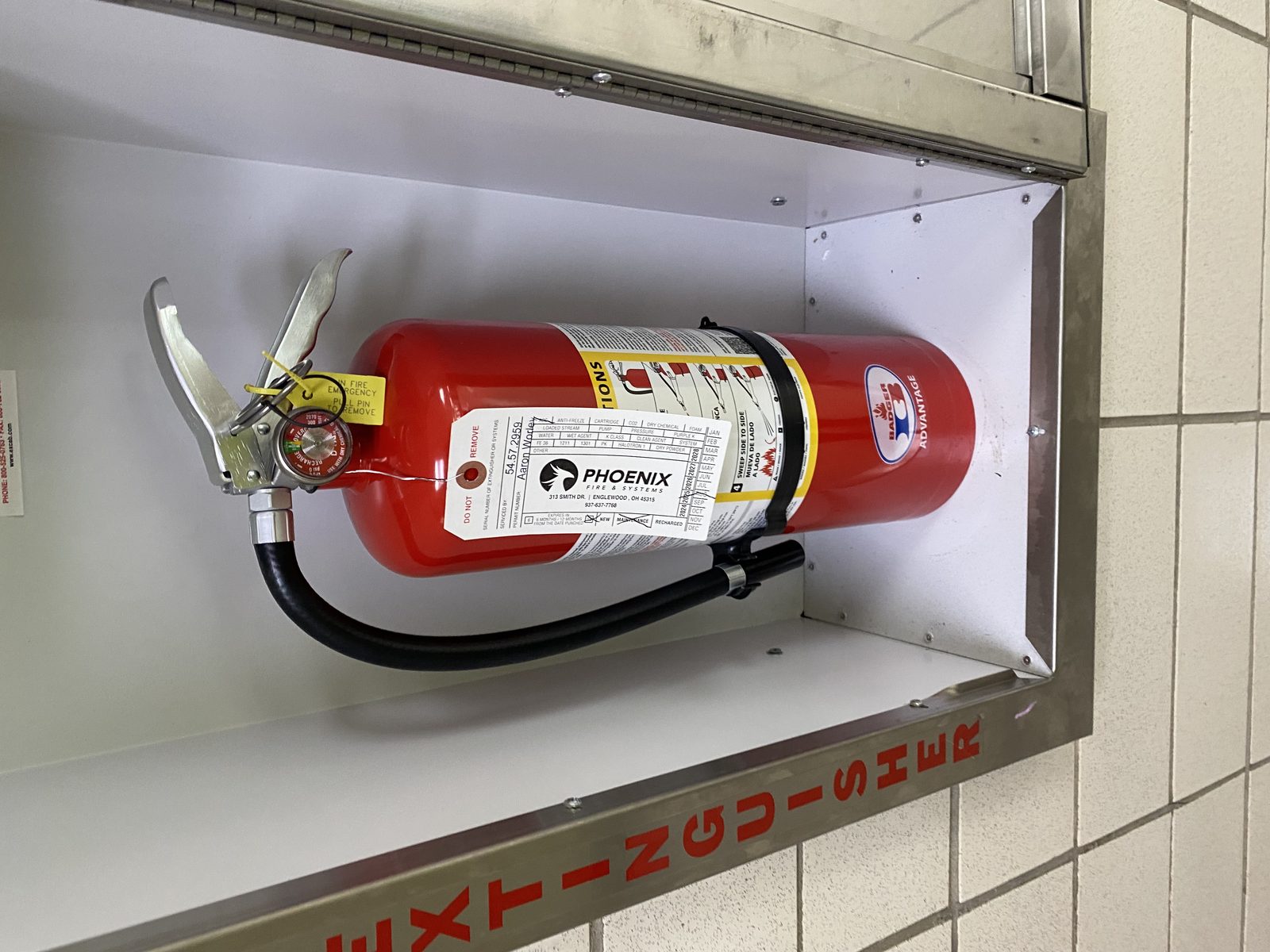 Fire extinguisher in a wall cabinet with a Phoenix inspection tag